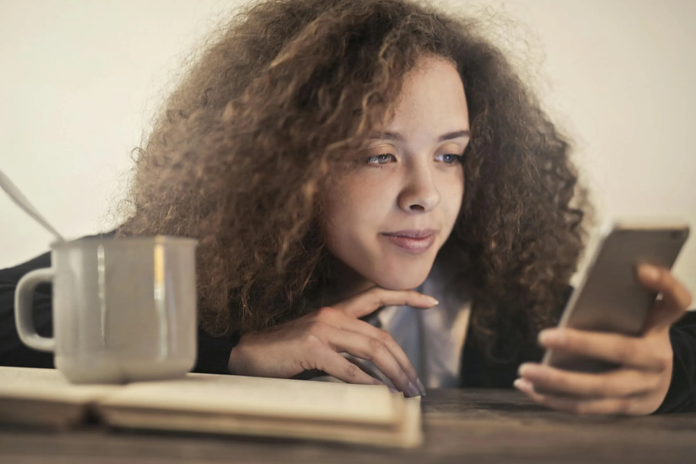 Young woman checking her phone settings while relaxing with a coffee